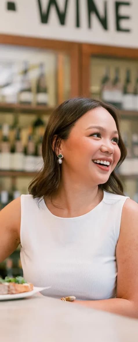 Bea Trinidad laughing in a white top at a wine bar